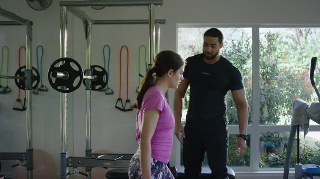 Personal trainers works with a female client in a small gym with weights