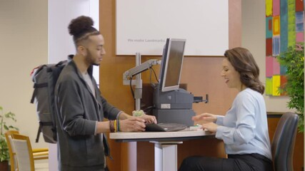 Professional bank teller assists a young customer at a bank