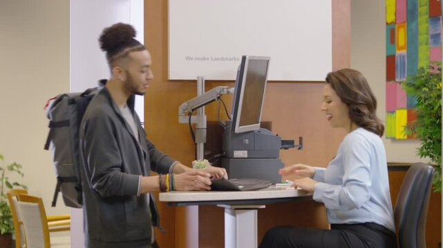 Professional bank teller assists a young customer at a bank
