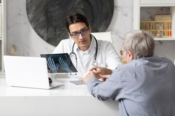Old man visiting young male doctor rheumatologist in modern clinic	
