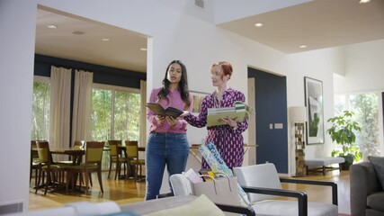 Two women look at color swatches while discussing interior design in a modern home