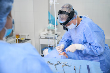 Clinic surgeon works with an assistant in an operating room