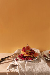 Delicious whole wheat healthy pancakes with raspberry, figues and copy space on the table with linen cloth