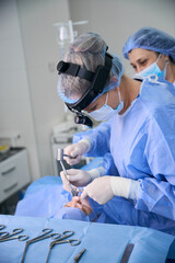 Female surgeon uses a surgical headlamp while working