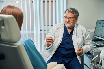 Fototapeta premium Elderly doctor gesturing during patient consultation