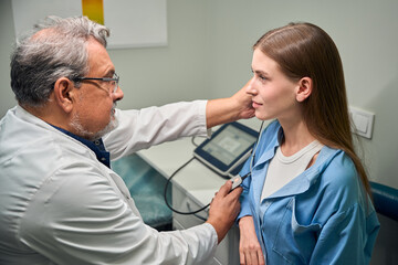 Obraz premium Caucasian doctor conducting ear examination on patient