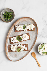 Homemade crispy toasts with ricotta, cottage cheese and herbs, microgreens, healthy eating, food for athletes