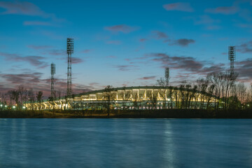 Night stadium illuminated by illumination on the shore at sunset.