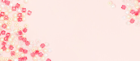 Banner with various acrylic beads scattered on a pink background. Place for text.