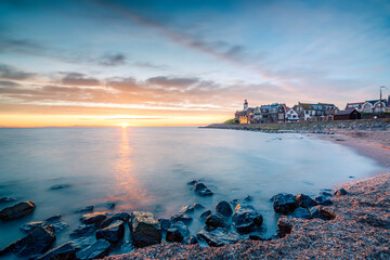 Sunset with a beautiful setting sun over the horizon near an old fishing village called Urk, with a heritage lighthouse
