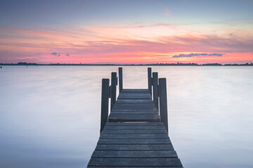 Obraz premium Weathered jetty on a lake at sunset. Serene tranquility scene with water and lake
