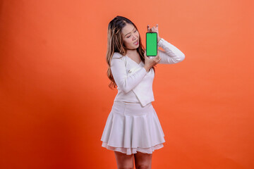 gesture young beautiful womangirl white top standing surprised to gadget both hands hold mobile phone screen, cellphone isolated orange background. for technology, promotion, lifestyle concept