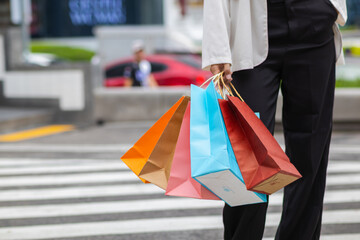 Businesswoman holding shopping paper bags in a shopping mall and is happy after shopping for her needs during the festival. Paper bags containing a lot of products are in hands of Asian businesswoman.