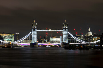 Tower Bridge in London at night, looking upriver towards the centre  of London with St Pauls in the background