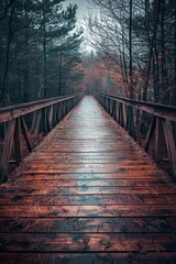 Fototapeta premium A beautiful wooden bridge in the forest, leading into a mysterious fog-covered path with autumn scenery.