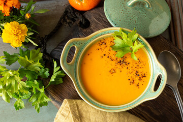 bowl of carrot cream soup with tangerines and chicken on a table
