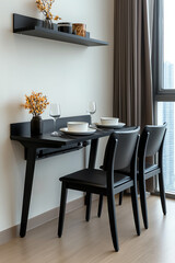 A side view of a small apartment dining space with a foldable dining table, two chairs, and wallmounted shelves