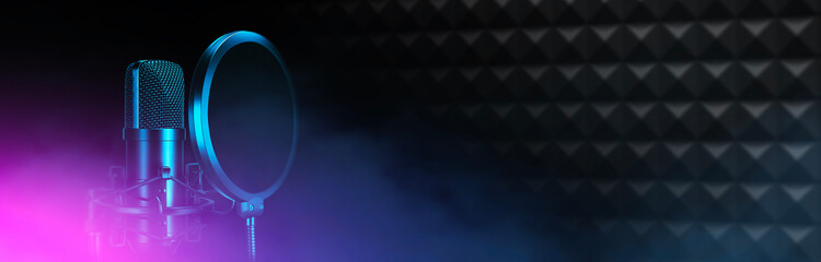 Studio microphone with pop up filters on the background of acoustic foam wall. Music production, radio broadcasting and podcast banner.