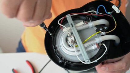 Master hand with screwdriver unscrews detail screwed with a screw of broken home appliance at table in workshop close up. Electronic devices repair service. Professional maintenance coffee maker in 4K