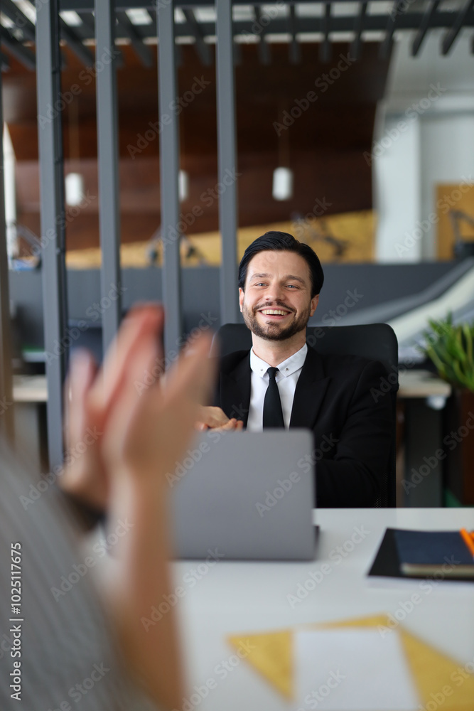 Poster a man in a suit is sitting at a desk with a laptop in front of him. he is smiling and he is happy. a