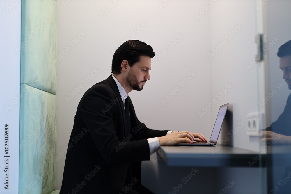 Poster a man in a suit is typing on a laptop. concept of focus and productivity, as the man is likely worki