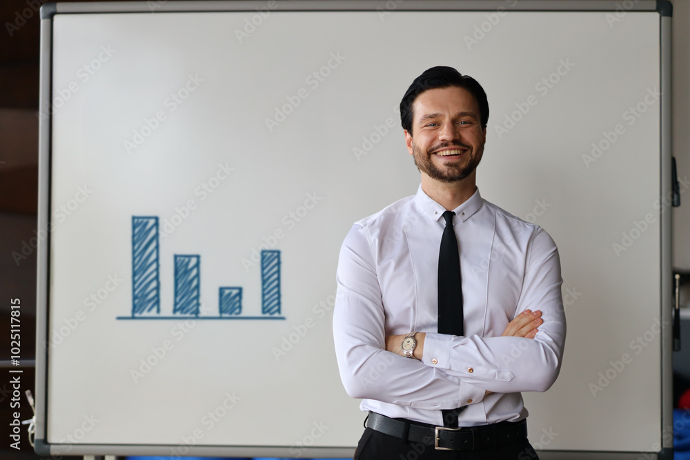 Poster a man in a suit stands in front of a white board with a graph on it. he is smiling and he is confide