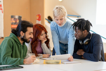 Diverse students collaborating on project, multicultural group studying with laptop in university library