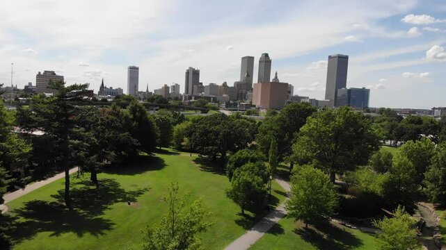 Tulsa, OK USA - August 30, 2022: Aerial drone video of downtown Tulsa skyline appearing over urban park area.