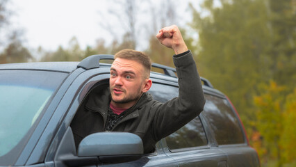 Angry Driver Expresses Frustration While Leaning out of a Car Window in a Wooded Area on a Cloudy Day