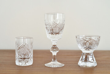 Different types of small elegant empty crystal glasses on the brown wooden table. . Close-up. Copy space. 
