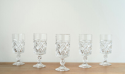 Elegant empty crystal glasses with high stem on the brown wooden table. Close-up. Copy space. Selective focus.