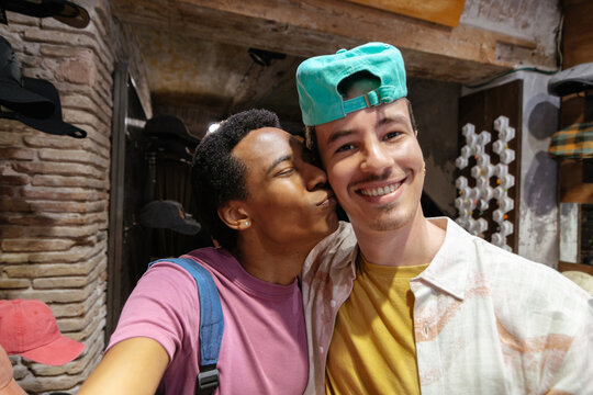 A multiethnic couple of two young men take a selfie in a store while shopping in the city.