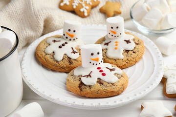 Delicious cookies with snowmen made of marshmallows on white table, closeup