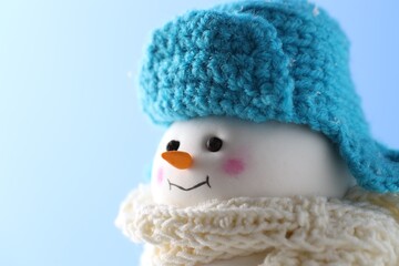 Cute decorative snowman against light blue background, closeup