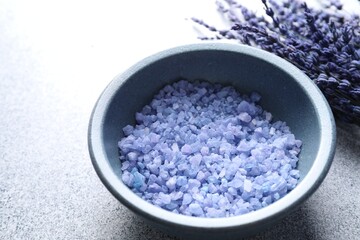 Natural sea salt and lavender flowers on grey table, closeup