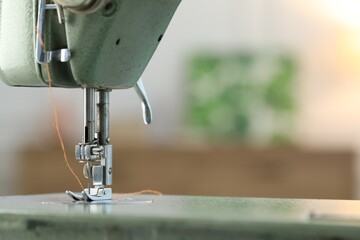 Sewing machine with thread on blurred background, macro view. Space for text