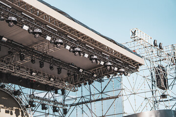 Steel stage structure with lighting setup outdoors. In the background, elements of the stage and frames for lighting equipment are visible. The construction is being prepared for a large outdoor event