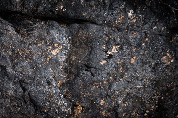 Dark textured stone surface with golden flecks. The stone is cracked, adding a sense of natural ruggedness and strength.