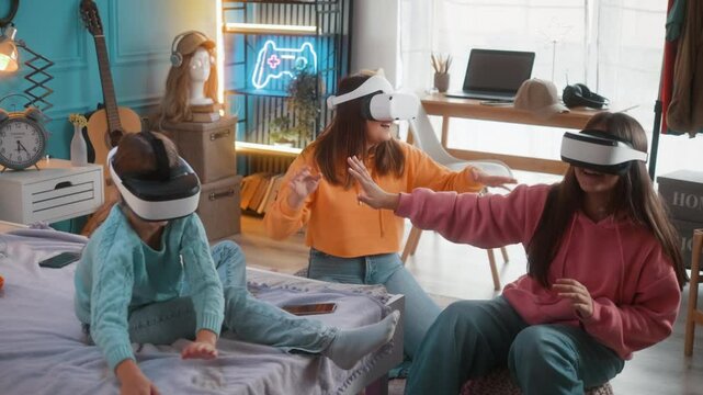 Teenager friends, only girls having fun playing video multiplayer games wearing virtual reality headsets in neon room at home