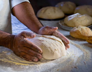 Obraz premium Baker kneading fresh dough on a floured surface in a rustic kitchen setting during the day