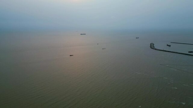 Aerial view of the foggy Bay of Bengal, with ships scattered across the water. In the distance, a bulkhead ship is visible, adding depth to the misty maritime scene