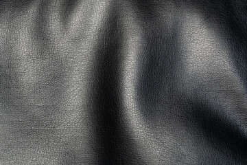 A background of textured black faux leather with a glossy finish. A photograph of a shiny, textured...