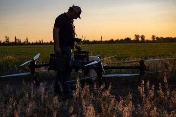 Agricultural drone pilot changing batteries at dusk.
