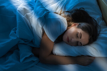 Woman sleeping in bed in morning at sunrise