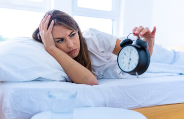 Pretty woman waking up as alarm clock ringing