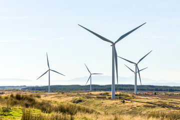 Wind farm turbines in wild Scottish moor land countryside with Isle of Arran in background on hazy day © Tosh Lubek
