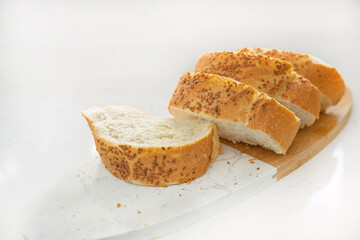 Sliced sesame bread on board isolated on white background, home baking concept
