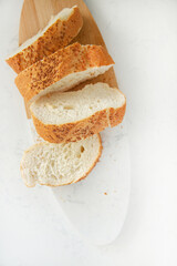 Sliced sesame bread on board isolated on white background, home baking concept