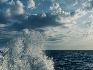 Sea wave spray water and sky clouds 