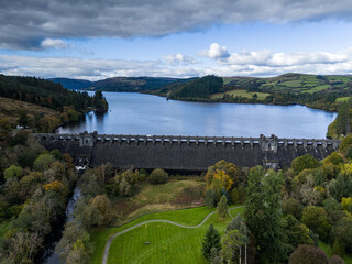 Large dam holding back water reservoir lake with dramatic sky